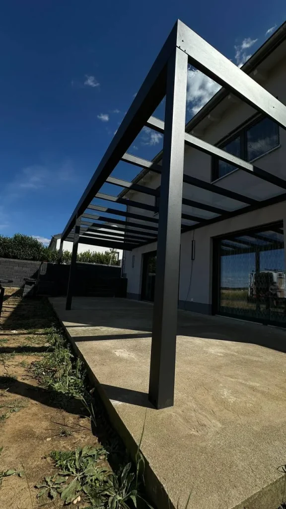 Alu-Terrassenüberdachung mit geneigtem Glasdach über Betonboden