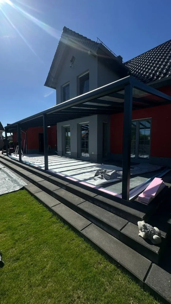 Terrassenüberdachung mit Glasdach an der Hauswand während der Montage