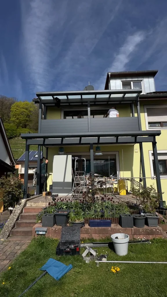 Terrassenüberdachung aus Aluminium unter dem Balkon eines zweistöckigen Hauses