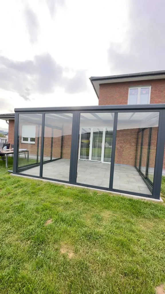 Verglaste Terrasse / Kaltwintergarten mit geschlossenen Glaselementen am Klinkerhaus