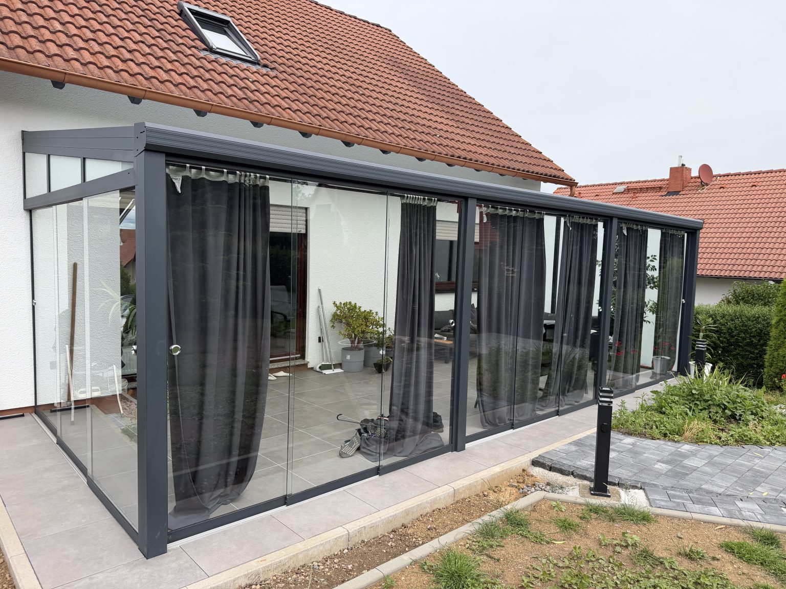 Ausgeführter Kaltwintergarten von Solny mit rahmenlosen Glasschiebeanlagen in Anthrazit
