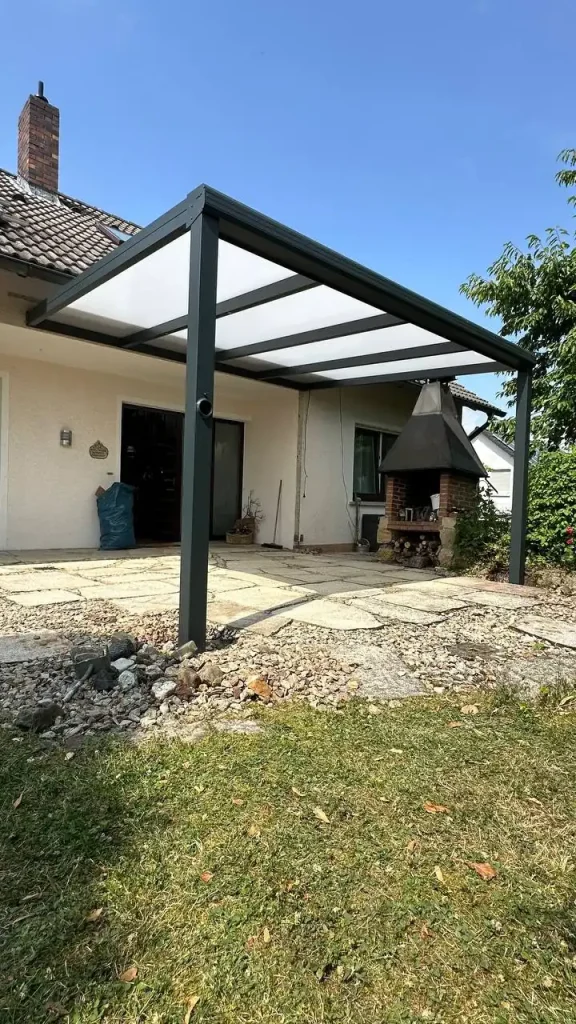 Alu-Terrassenüberdachung mit hellen Dachplatten an einem Haus mit Solaranlage