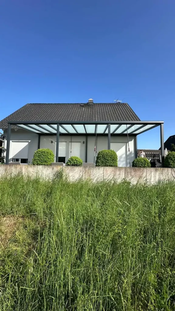 Einfamilienhaus mit angebauter Terrassenüberdachung bei blauem Himmel