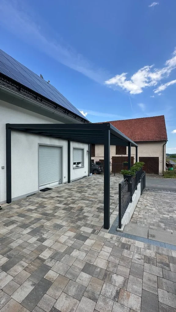 Alu-Terrassenüberdachung an einem Einfamilienhaus mit Solarmodulen