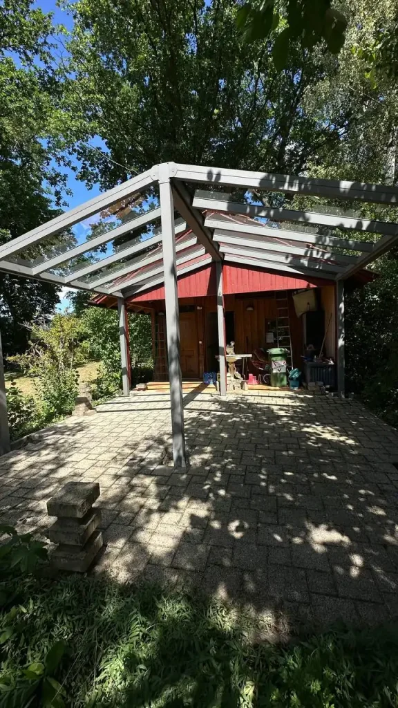 Alu-Terrassenüberdachung mit Glasdach über gepflasterter Terrasse