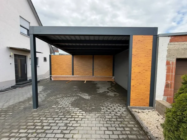 Aluminium-Carport mit Glasdach und Seitenverkleidung an gepflasterter Einfahrt