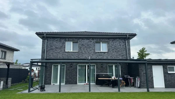 Terrassenüberdachung mit Glasdach an der Rückseite eines Einfamilienhauses