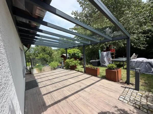 Terrassenüberdachung mit Glasdach über einer Holzterrasse – Projekt von Solny