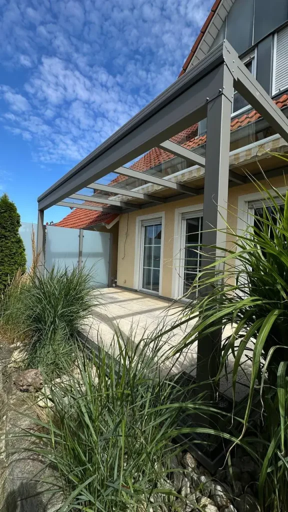 Terrassenüberdachung mit Glasdach und Sichtschutzelement an der Terrasse