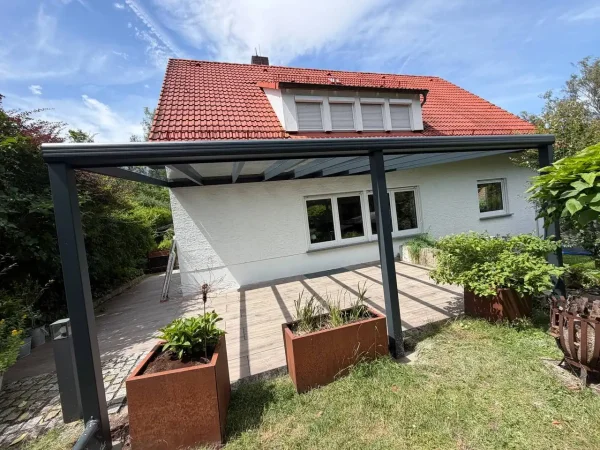 Terrassenüberdachung mit Glasdach an einem Haus mit rotem Ziegeldach