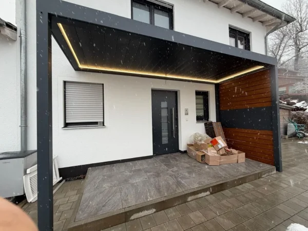 Aluminium-Terrassendach mit LED-Lichtband an der Hauswand bei Schneefall
