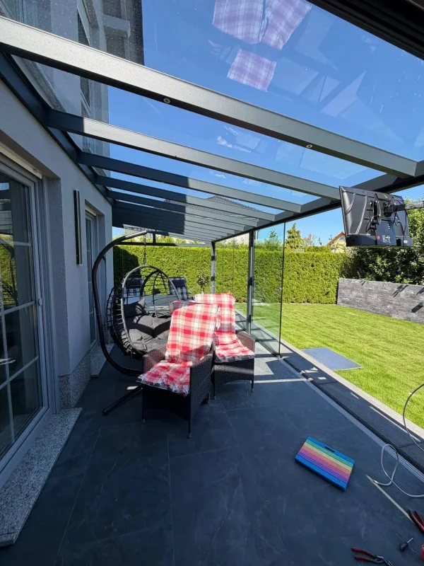 Terrassenüberdachung aus Aluminium mit Glasdach und Hängesessel auf Fliesenboden