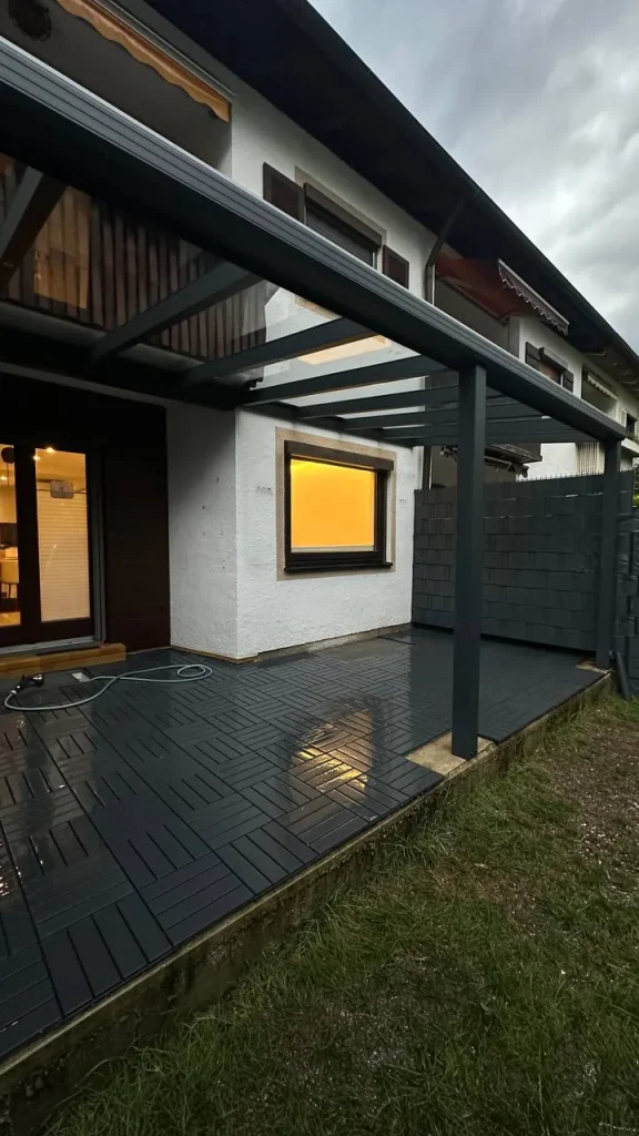 Terrassenüberdachung aus Aluminium mit Glasdach über dunklen Terrassendielen – Projekt von Solny