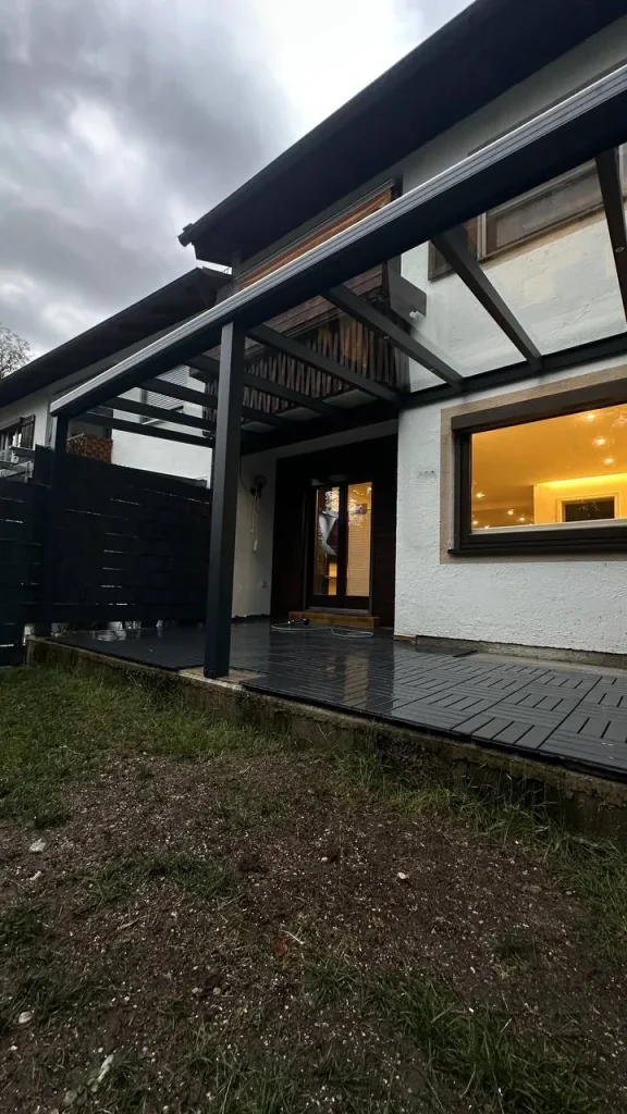 Überdachte Terrasse mit Glasdach mit Blick auf das beleuchtete Fenster