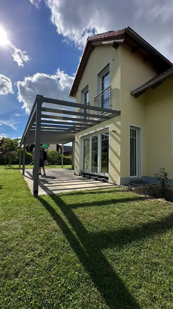 Terrassenüberdachung aus Aluminium an der Hausseite unter dem Balkon