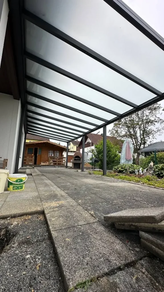 Blick unter die Terrassenüberdachung mit Glasdach auf den Gartenweg – Projekt von Solny