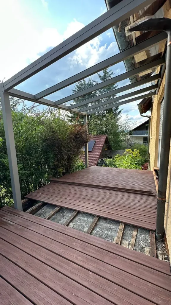 Terrassenüberdachung mit Glasdach über noch unfertigen Terrassendielen