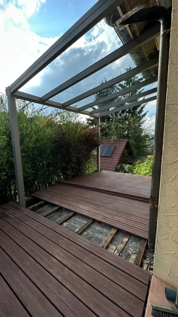Terrassenüberdachung mit Glasdach über teilweise verlegten Terrassendielen