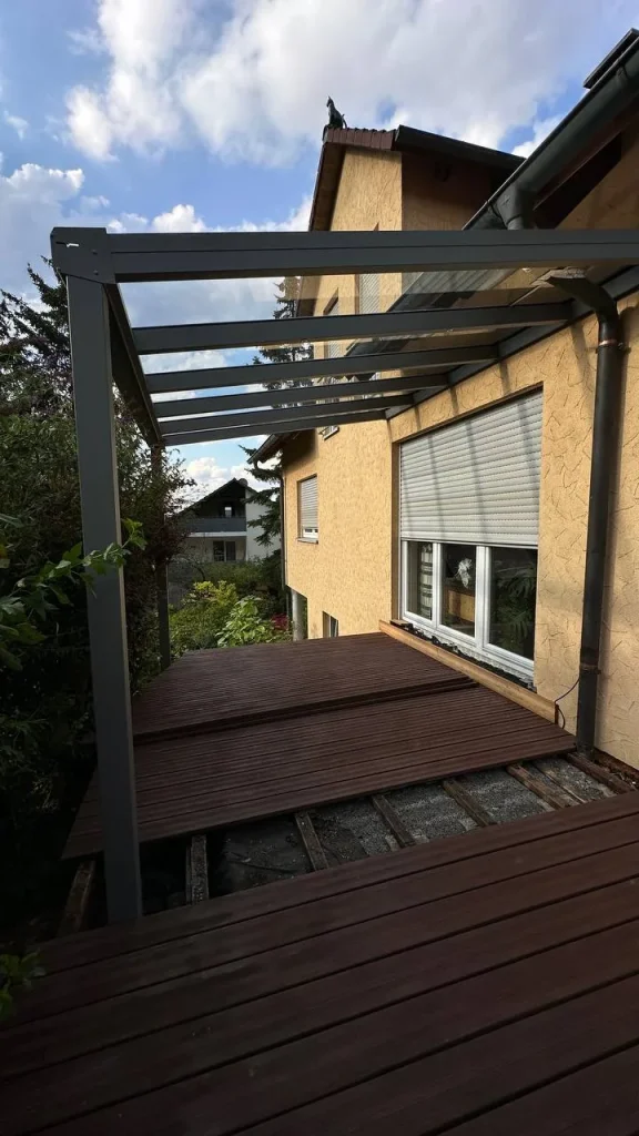 Terrassenüberdachung mit Glasdach über einer im Bau befindlichen Holzterrasse – Projekt von Solny