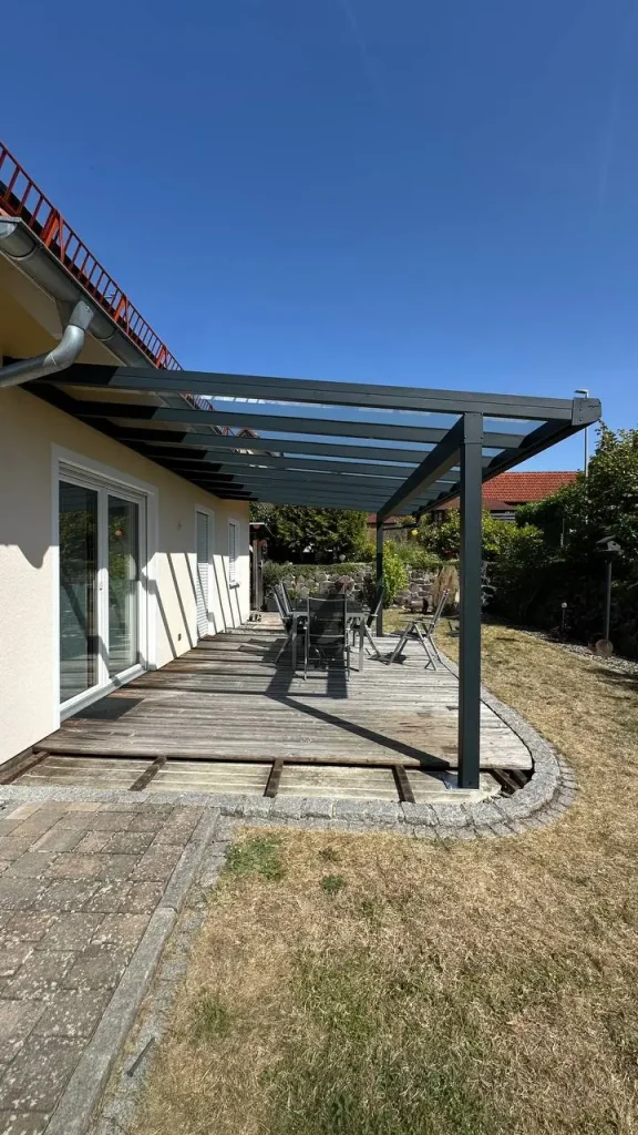 Terrassenüberdachung in Anthrazit mit Glasdach über einer Holzterrasse