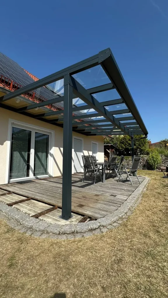 Terrassenüberdachung mit Glasdach über einer Holzterrasse im Garten