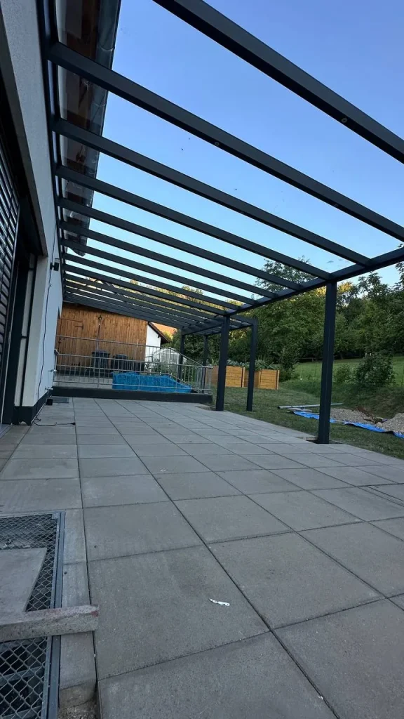 Terrassenüberdachung aus Aluminium mit Glasdach mit Blick auf den Pool