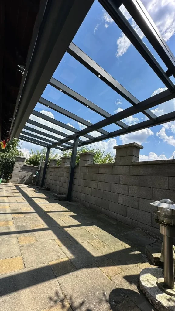 Terrassenüberdachung aus Aluminium mit Glasdach an einer Hausecke