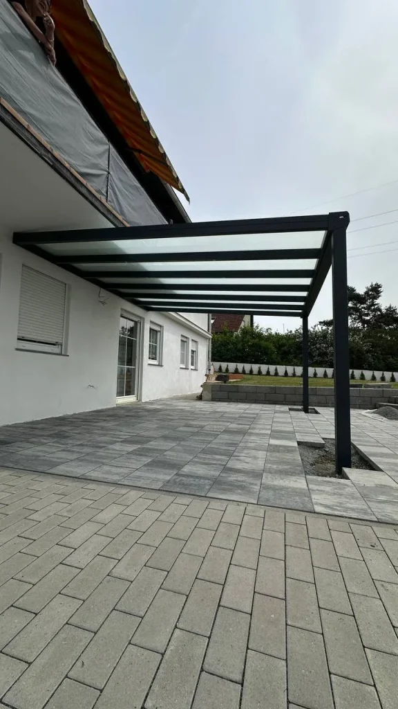 Terrassenüberdachung aus Aluminium mit Glasdach neben einer vorhandenen Markise