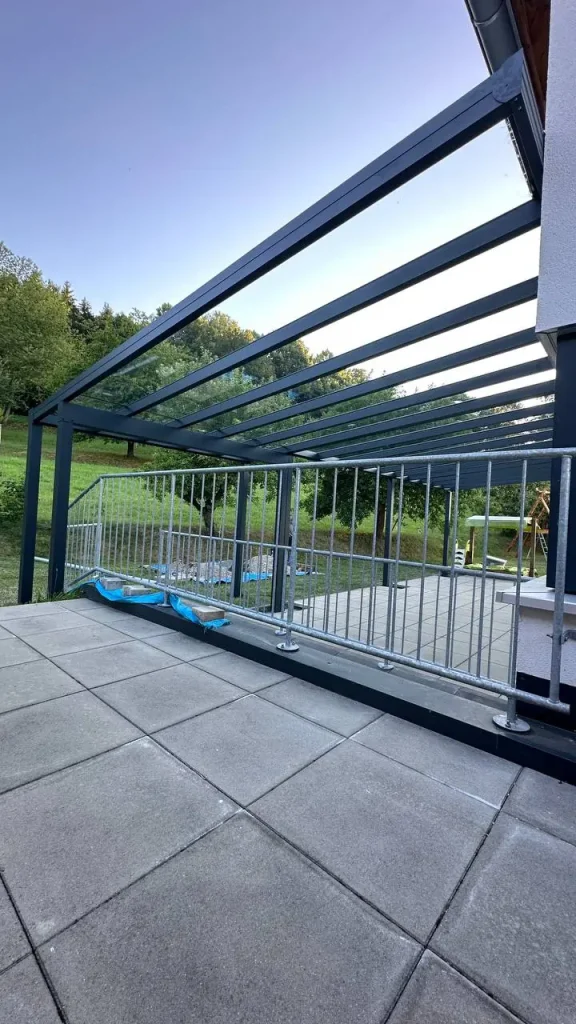 Terrassenüberdachung aus Aluminium mit Glasdach über gepflasterter Fläche