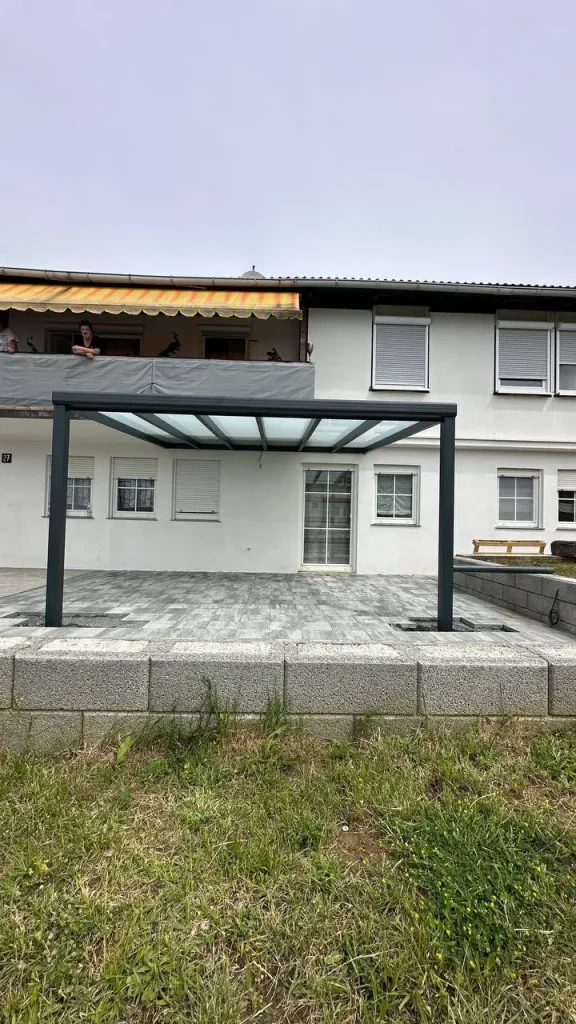 Terrassenüberdachung aus Aluminium an der Hausecke mit angrenzender Rasenfläche