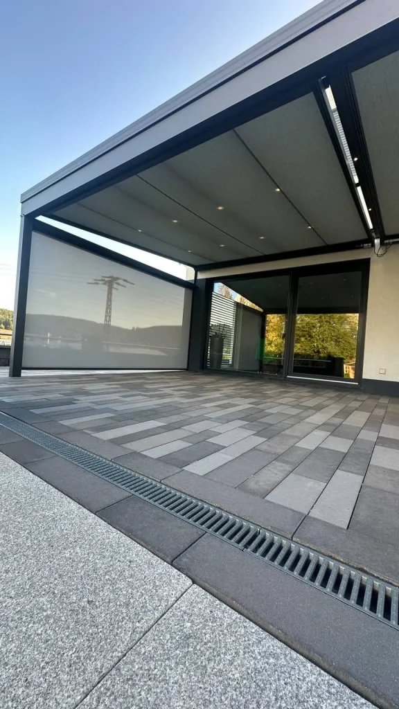 Terrassenüberdachung aus Aluminium mit LED-Lichtleiste und teilweise geschlossenem Seitenelement